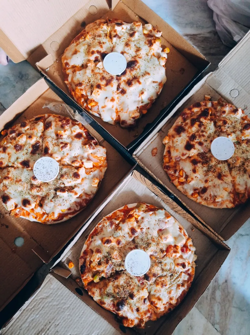 Pizzas em caixas de papelão abertas, prontas pra entrega